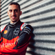 A photo of Nissan driver Sébastien Buemi leaning against a garage door.